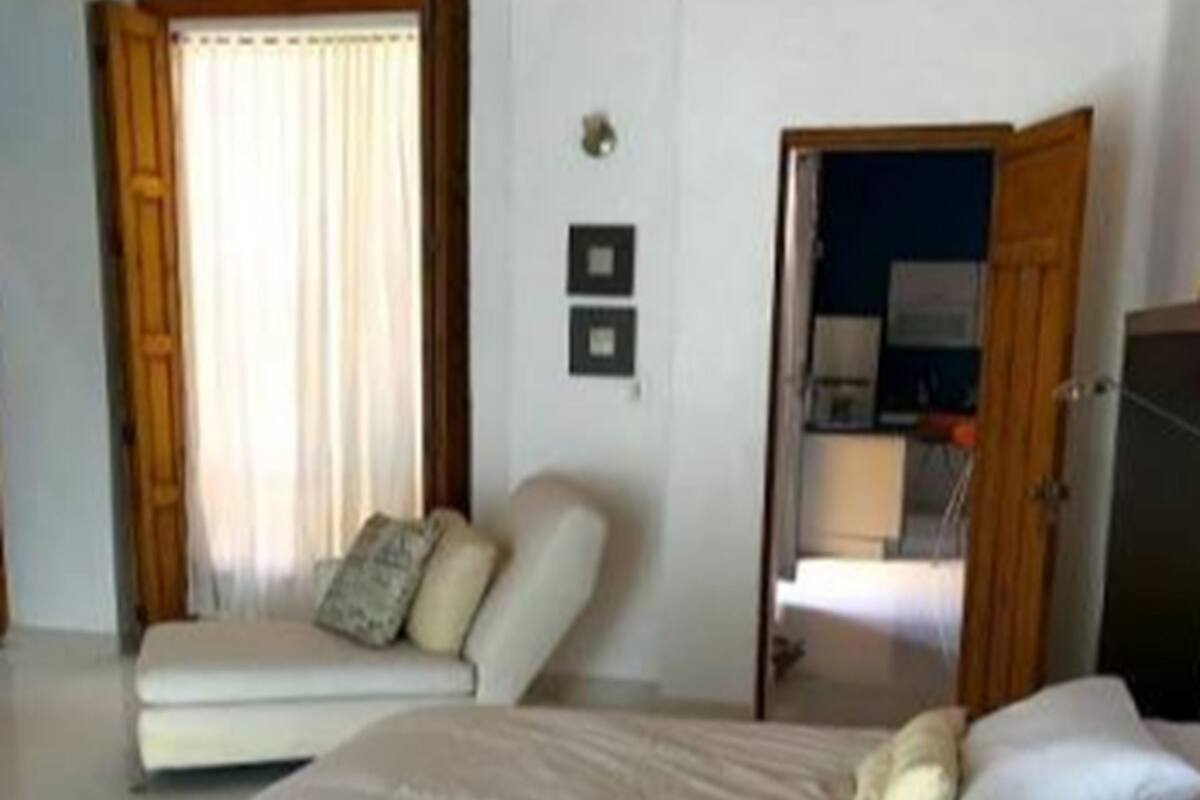 A bedroom with a large bed, a sofa, and a door leading to another room.