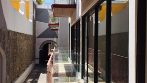 A narrow corridor with a glass railing, leading to a building entrance. - Lofts El Sueño (Puebla)