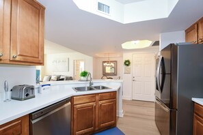 A kitchen with wooden cabinets, a stainless steel refrigerator, a dishwasher, and a built-in oven. - Open-concept, fully equipped condo w/private balcony in Destin! ☀🌴 (Destin)