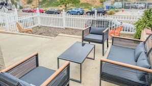 An outdoor seating area with wicker furniture and a white fence.