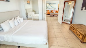 A hotel room with a large bed, a wooden dresser, a mirror, and a painting on the wall.