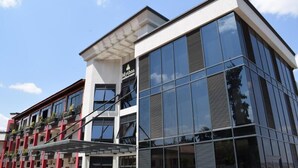 A modern building with large glass windows and a sign for 'Mythos'. - Mythos Boutique Hotel (Kigali)