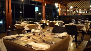A restaurant with multiple tables set for dining, featuring a bar area in the background. - Mythos Boutique Hotel (Kigali)