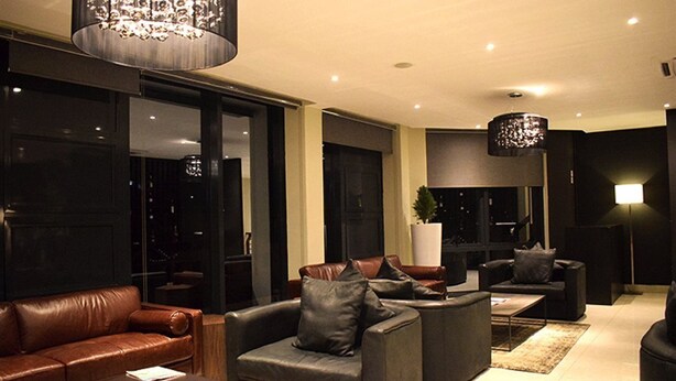 A modern living room with leather sofas, a coffee table, and a chandelier. - Mythos Boutique Hotel (Kigali)