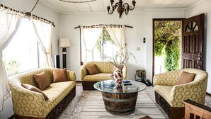 A room with three patterned sofas, a glass coffee table, and a chandelier. - Posada San Antonio (Valle de Guadalupe)