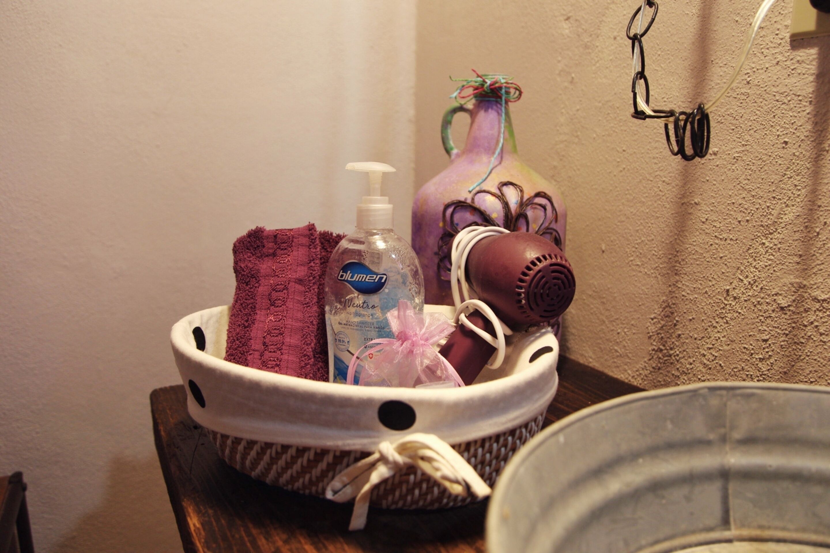 A bathroom sink with a mirror, a towel, a bottle of hand soap, and a hairdryer.