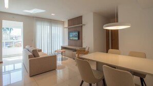 Un salon moderne avec un canapé, une table à manger, des chaises et un téléviseur.