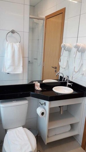 A bathroom with a toilet, sink, towel rack, and hair dryers. - STARLIS HOME - Versátil (Cuiabá)