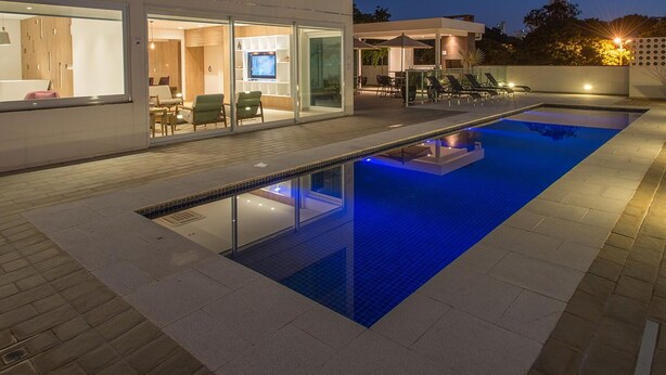 Une piscine extérieure moderne dotée d’un espace détente vitré et d’un bar.