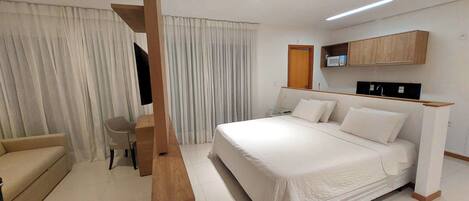 Ein Hotelzimmer mit Bett, Schreibtisch, Stuhl, Fernseher und Mikrowelle.