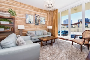 A living room with a sofa, armchair, wooden coffee table, and a chandelier.
