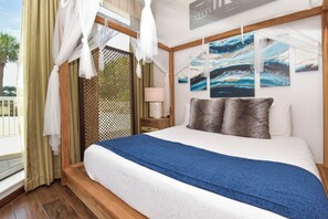 A bedroom with a large bed, a nightstand, a lamp, and artwork on the wall.