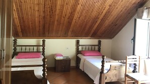 Ein Zimmer mit zwei Holzbetten, einem kleinen Nachttisch und einem Stuhl.