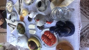 Ein Tisch ist mit Frühstücksleckereien gedeckt, darunter Eier, Toast, Tomaten und eine Banane.