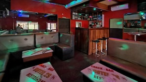 A bar area with booths and a bar counter. There are signs indicating a snack bar and a hotel. - Hôtel 2S (Douala)
