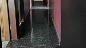 A hallway with a wooden door on the left, a white door at the end, and a ceiling light. - Hôtel 2S (Douala)