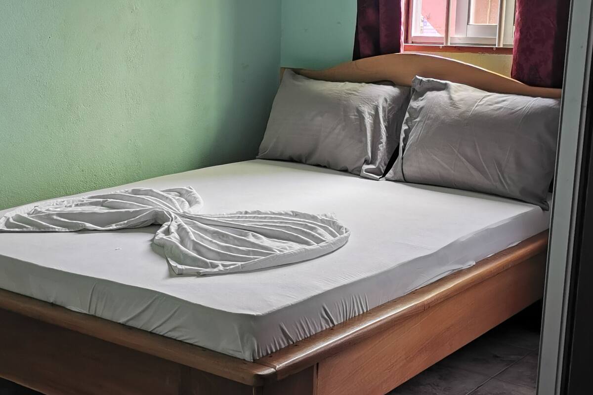 A single bed with a wooden frame, white bedding, and two pillows.