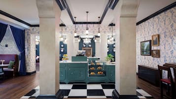 A hotel lobby with a checkered floor, teal-colored reception desk, and a seating area with a blue curtain.