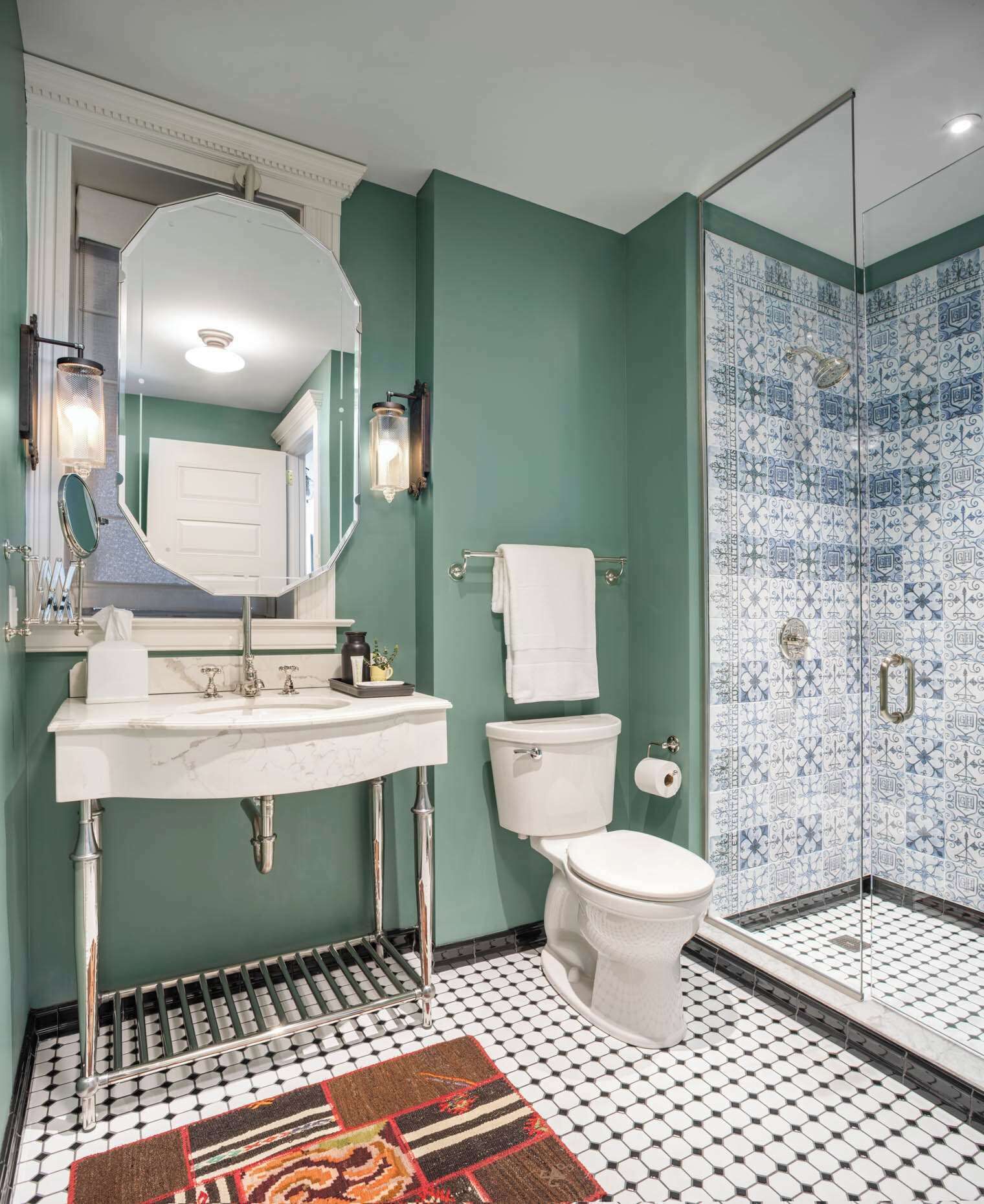 A bathroom with a white sink, a toilet, a shower with blue patterned tiles, and a black and white tiled floor.