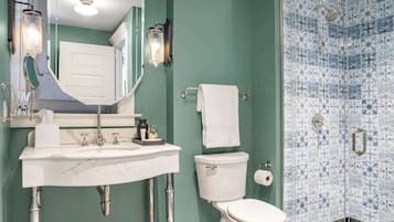 A bathroom with a white sink, a toilet, a shower with blue patterned tiles, and a black and white tiled floor.