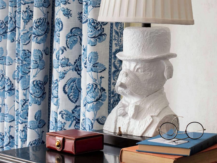 Een bureau met een lamp, boeken, een buste en een rode doos.