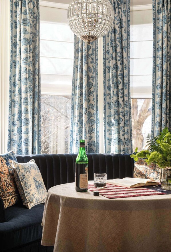 Une pièce chaleureuse avec un canapé bleu foncé, une table sur laquelle se trouvent une bouteille, un verre et un livre.