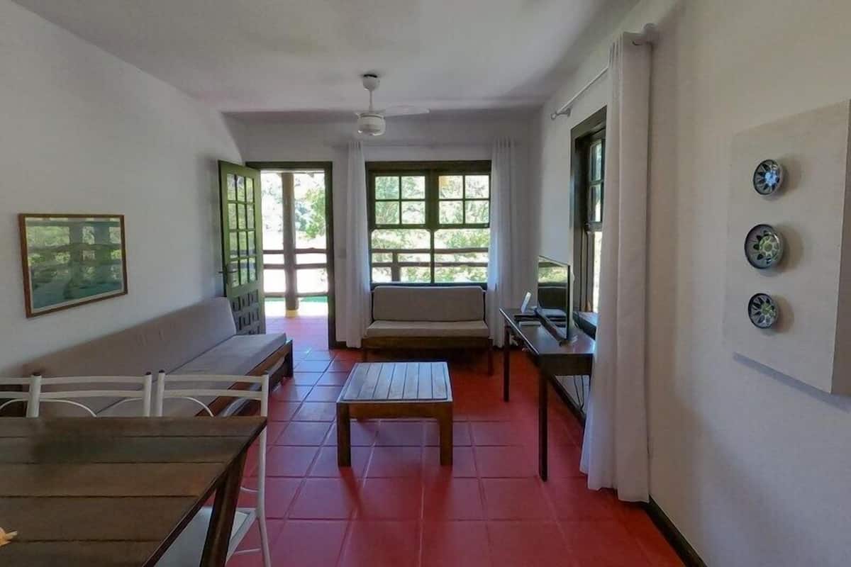 Une pièce avec une table en bois, un canapé et une fenêtre donnant sur un paysage verdoyant.