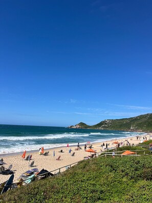A beach with people, umbrellas, and chairs. - Residencial Cabanas da Praia Mole (Florianópolis)