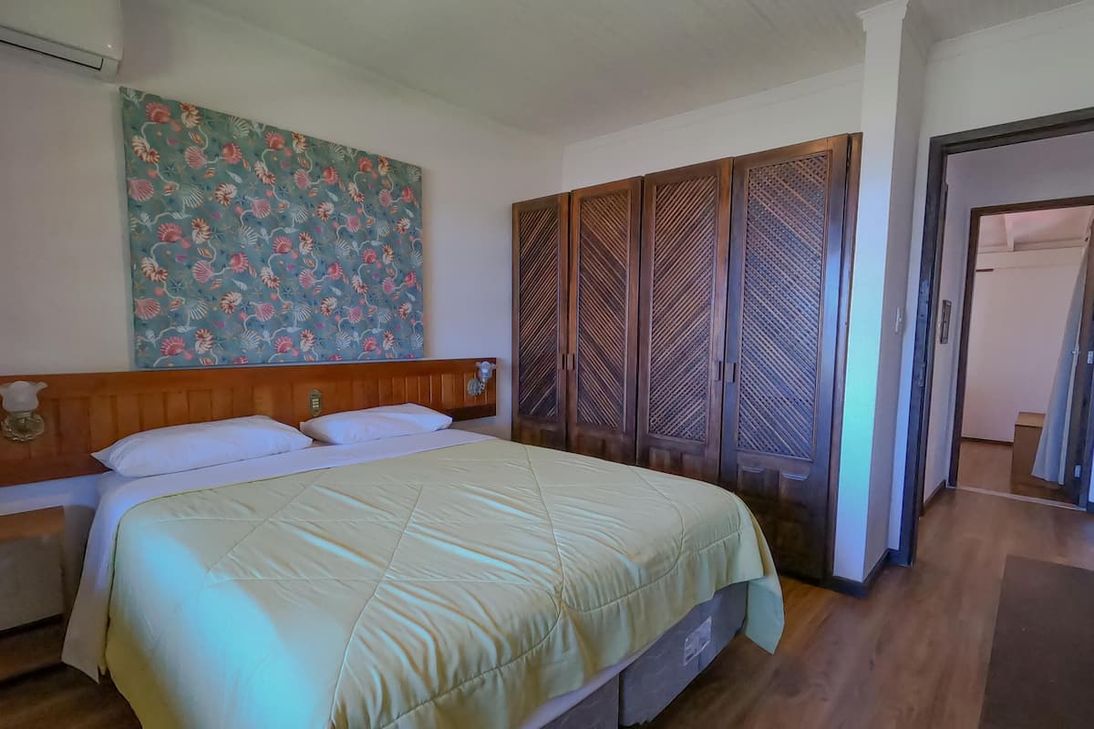 Une chambre avec un lit, une décoration murale à motifs floraux, une armoire à motifs géométriques et un couloir menant à une autre pièce.
