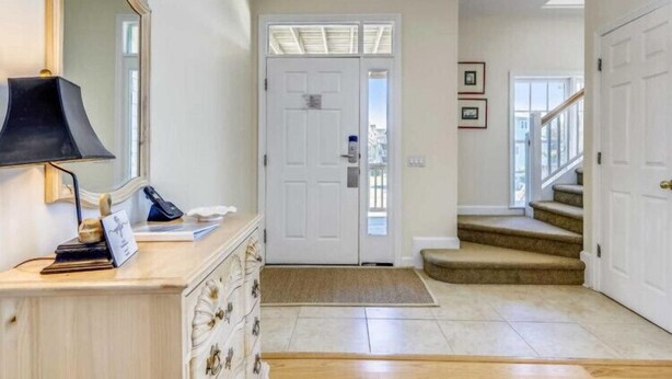 A hallway with a white door, a desk with a lamp, and a staircase leading to an upper floor.