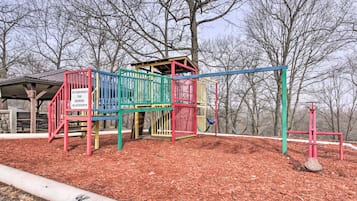Une aire de jeux avec une structure d’escalade et une balançoire, entourée d’arbres et recouverte de paillis.