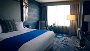 Una habitación de hotel con una cama grande, una silla, una mesita y una lámpara.