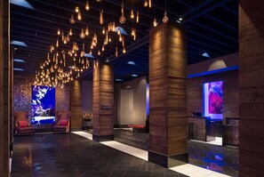 A modern lobby with exposed wooden beams, a stage with a performer, and a large digital screen. - Wind Creek Casino & Hotel Montgomery (Montgomery)