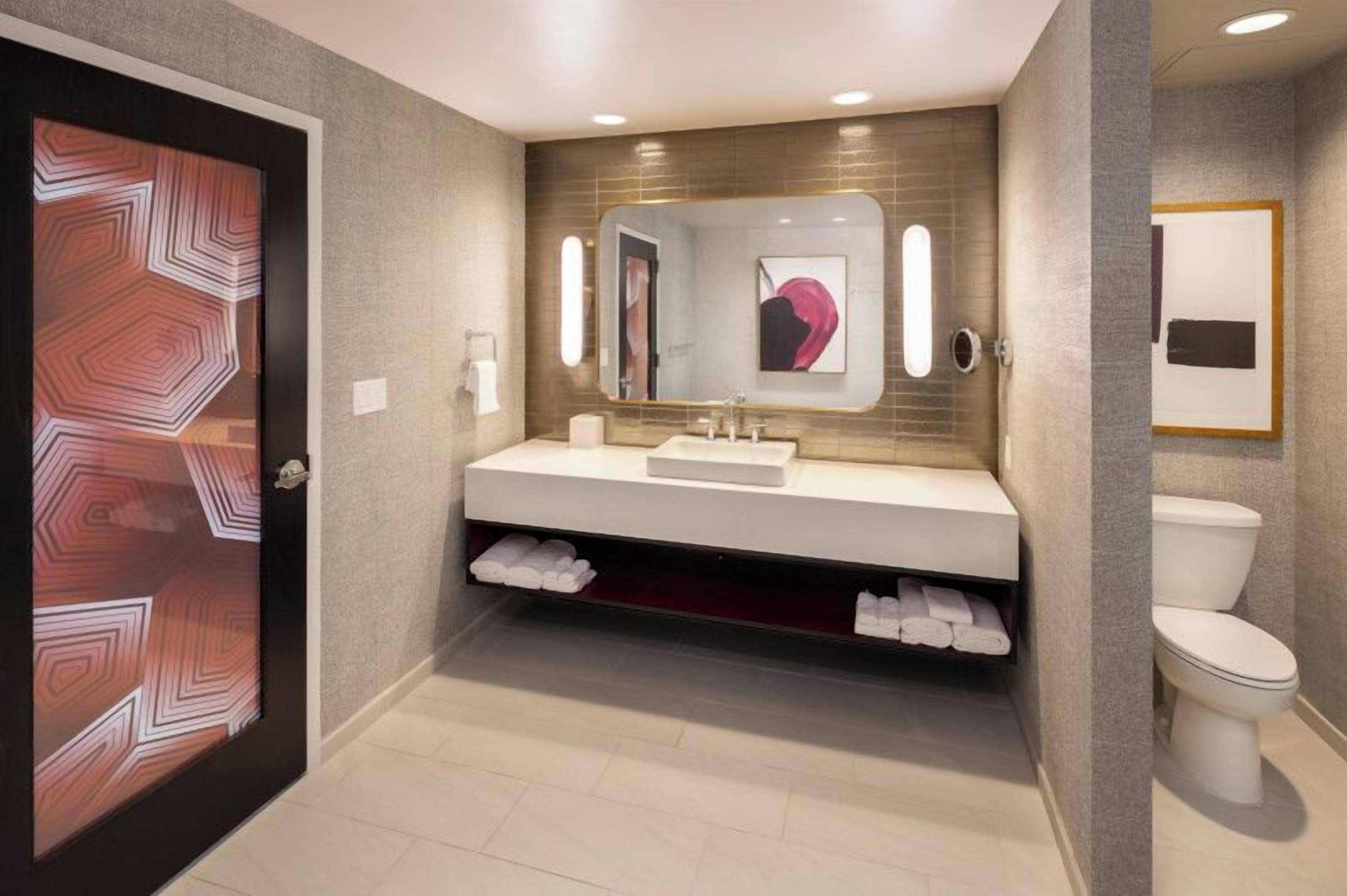 Ein modernes Badezimmer mit Waschtisch, Waschbecken, Spiegel und Toilette.
