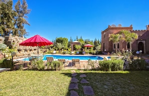 Una piscina al aire libre, sombrillas, sillones reclinables de piscina