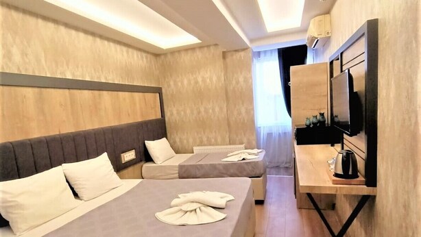 A modern hotel room with a large bed, a desk with a flat-screen TV, and a small seating area. - Avcilar Elit Hotel (Istanbul)