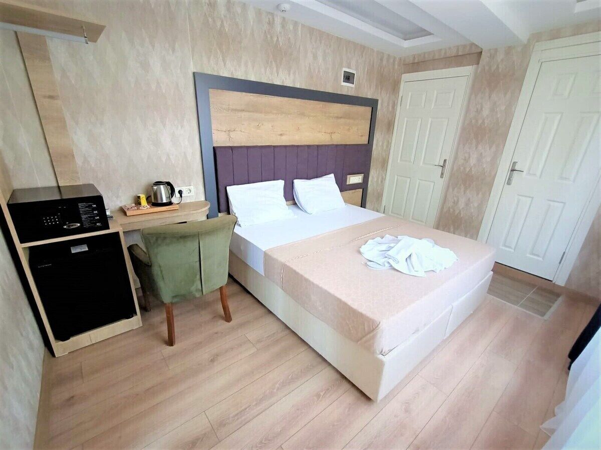 Un dormitorio con cama, escritorio con computadora, cafetera y armario.