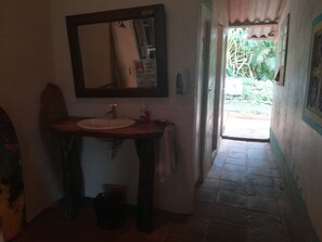 A bathroom with a sink, mirror, and a towel hanging on the wall. - Tiki Lodge Bar & Restaurant - Hostel (Hicaco)