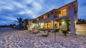 A beachfront property with a two-story house, a balcony, and a patio area with lounge chairs. - Penelope Beach House (San Andrés)