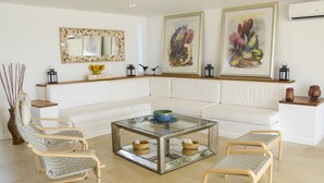 A modern living room with a white sofa, a glass coffee table, and wicker chairs. - Penelope Beach House (San Andrés)