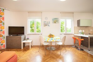 Una cocina moderna con comedor, piso de madera y ventanas amplias.