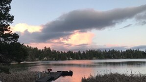Näkymä järvelle, jossa on laituri, piknikpöytä ja tuoleja.