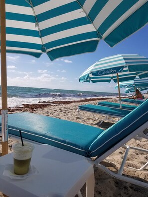 Relax in comfort under a shaded umbrella, with access to the sandy beach and the soothing sound of waves.