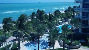 Un resort con piscina, palmeras y vistas al océano.