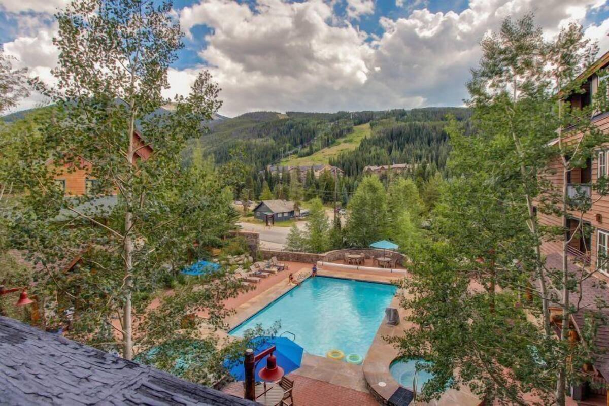 A pool area with a view of a mountainous landscape, surrounded by trees and buildings.