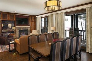 A spacious living room with a fireplace, a television, and a dining area with a table and chairs.