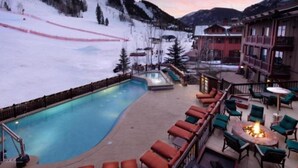 A poolside area with lounge chairs and a fire pit, overlooking a snowy mountain landscape. - Aspen Ritz Carlton 3 Bed (Aspen)