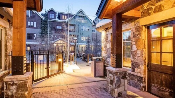 A stone building with a wooden porch and a brick pathway. - Luxury 3 Bedroom Breckenridge Vacation Rental with Mountain Views Steps from Historic Main Street (Breckenridge)