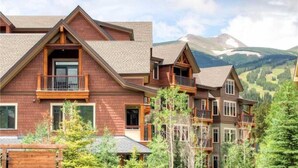 A multi-story lodge with a prominent balcony, set against a mountainous backdrop. - Luxury 3 Bedroom Breckenridge Vacation Rental with Mountain Views Steps from Historic Main Street (Breckenridge)