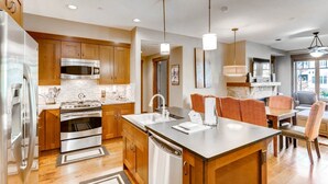 A modern kitchen with stainless steel appliances, wooden cabinets, and a central island. - Luxury 3 Bedroom Breckenridge Vacation Rental with Mountain Views Steps from Historic Main Street (Breckenridge)